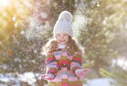 Happy little girl playing with snow in the park