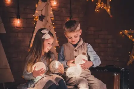 A boy and a girl playing with toys on a Christmas Eve.