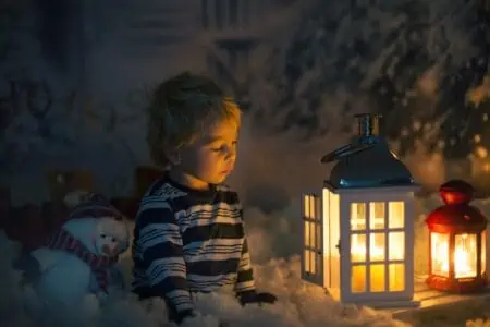 Little boy looking at the candle flame in the dark room