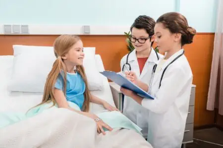 Two little kids dressed as doctors treating a patient.