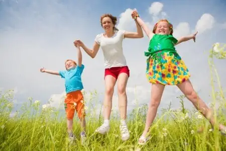 Happy mother playing with her son and daughter in the field.