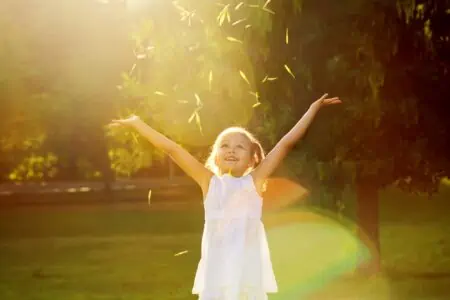 Cute little girl in a white dress playing in the park