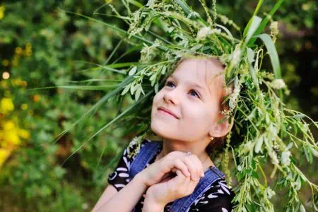 Happy little girl wearing a wreath playing in the park