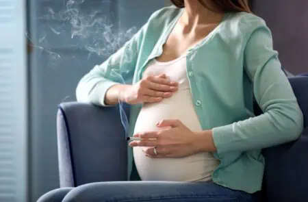 Pregnant woman smoking cigarette at home