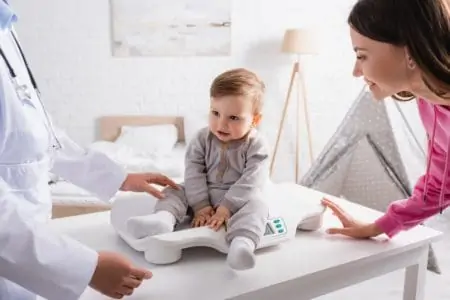 Doctor checking toddler's weight