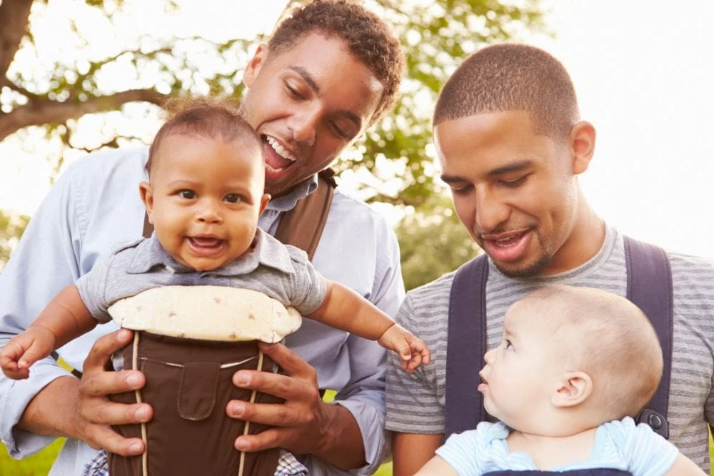 Two fathers wearing their babies in a carrier